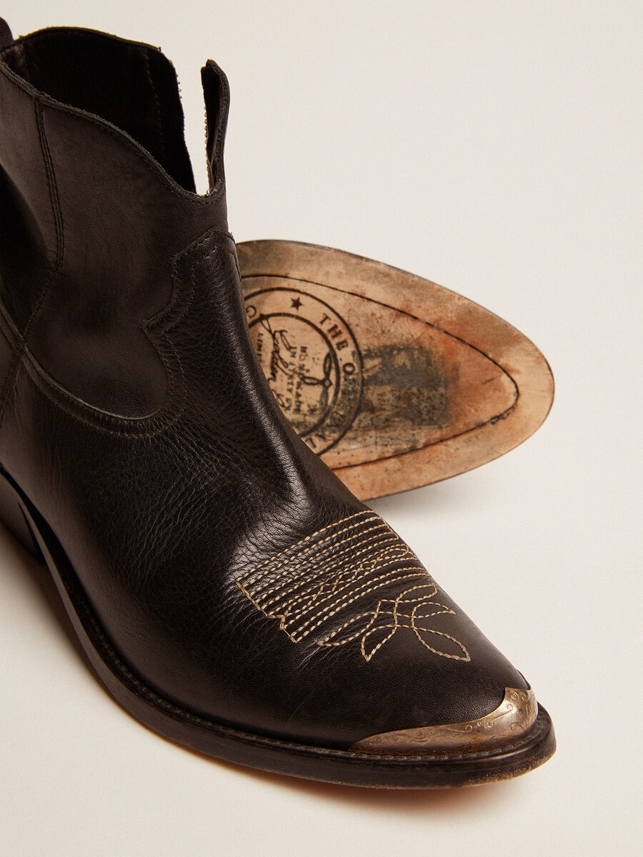 unga ankelboots i svart läder med sandfärgad broderi